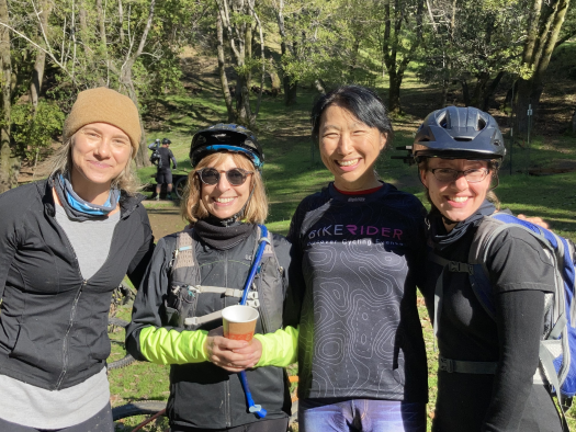 Four smiling women in post-ride gear