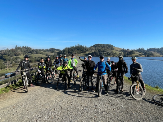 Group of about 15 mountain bikers near a lake